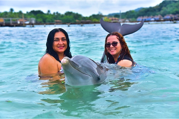 Family meeting a dolphin in shallow water with a trainer